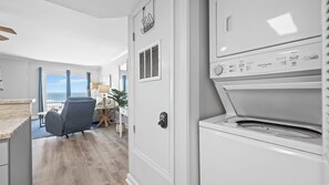 A modern kitchen with a built-in washer and dryer, a wooden floor, and a view of the ocean through large windows. - Splendid East Beach Gulf Front ~ Sleeps 6 (Gulf Shores)