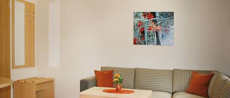 A living room with a sofa, a small table with a vase, a wooden bench, and a painting on the wall.