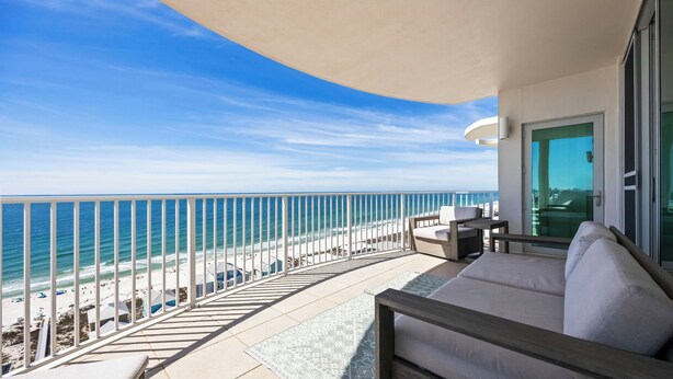 A balcony with a view of the beach and ocean, a sofa, and a table. - Luxury 4BR Condo w/ private beach access & heated pool (Gulf Shores)