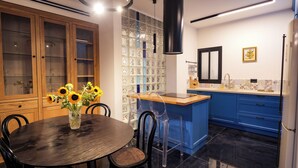 A modern kitchen with a round dining table, blue cabinets, and a glass backsplash. - Spacious 5-Room Apartment Near the Sea – Bat Yam (Bat Yam)