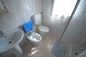 A bathroom with a sink, bidet, toilet, and a shower area. - Holiday apartment with air conditioning, garden and terrace (Lignano Sabbiadoro)