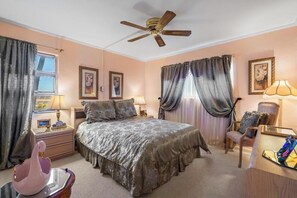A bedroom with a bed, nightstands, a chair, a desk, a ceiling fan, and curtains. - Menehune Shores #301 - Oceanfront Shoreline Location with Inviting Living Spaces (Kihei, Maui)