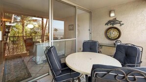 Un balcón con puerta de cristal, una mesa redonda y cuatro sillas.