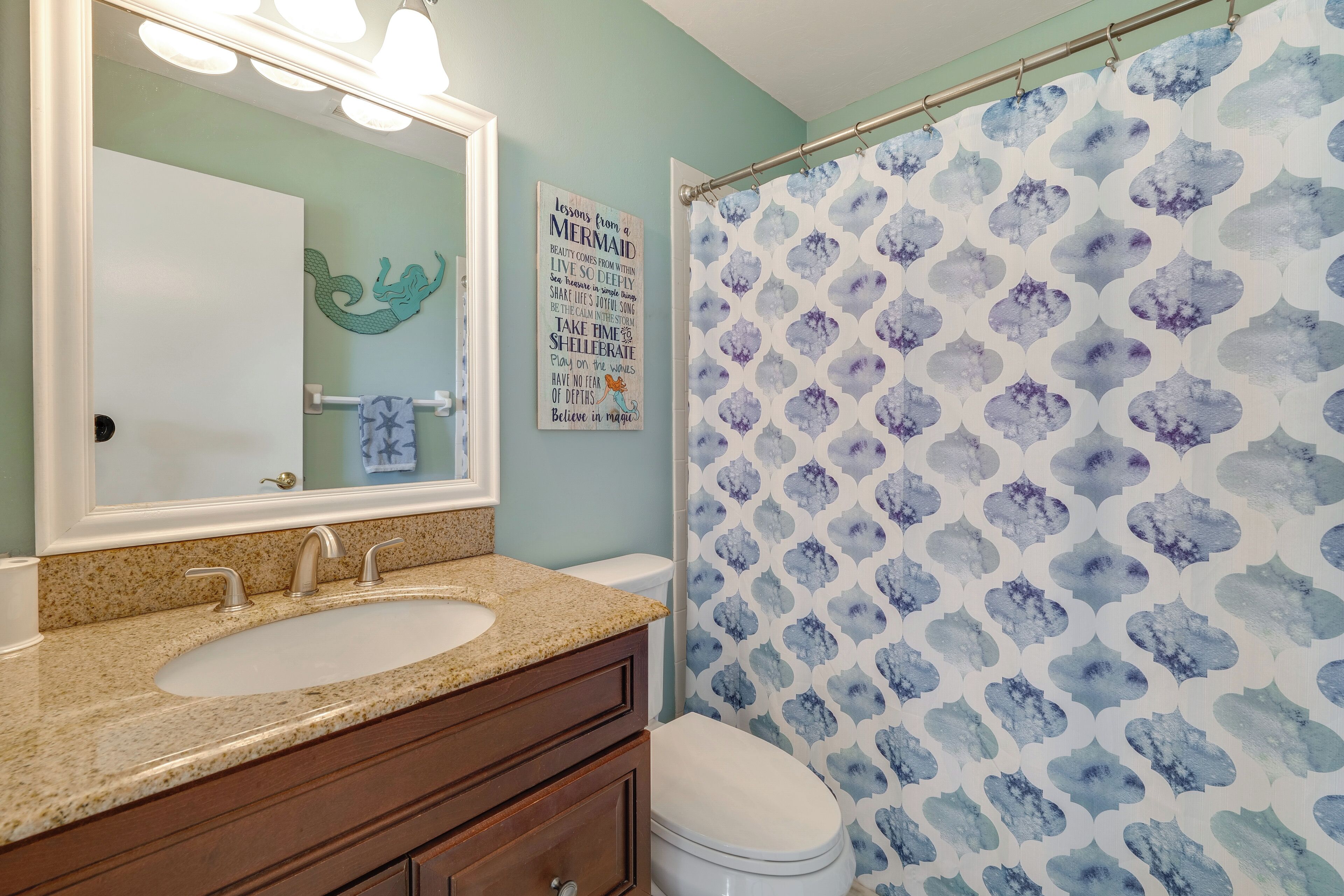 A bathroom with a sink, vanity, and a shower curtain with a blue and white pattern.