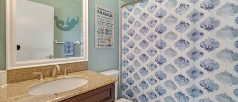 A bathroom with a sink, vanity, and a shower curtain with a blue and white pattern.