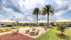 A courtyard with outdoor seating, palm trees, and a well-maintained lawn. - Sebring Fairway Villa Golf, Lake, Track, & Pools (Sebring)