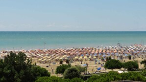 Une plage dotée de nombreux parasols et de chaises longues, ce qui indique qu’il s’agit d’un complexe hôtelier balnéaire.