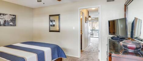 A bedroom with a bed, a ceiling fan, a dresser, and a television.