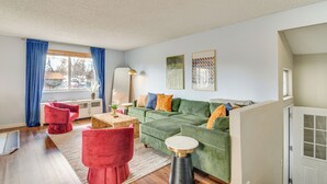 Ein modernes Wohnzimmer mit einem grünen Sofa, roten Sesseln und einem Holztisch.