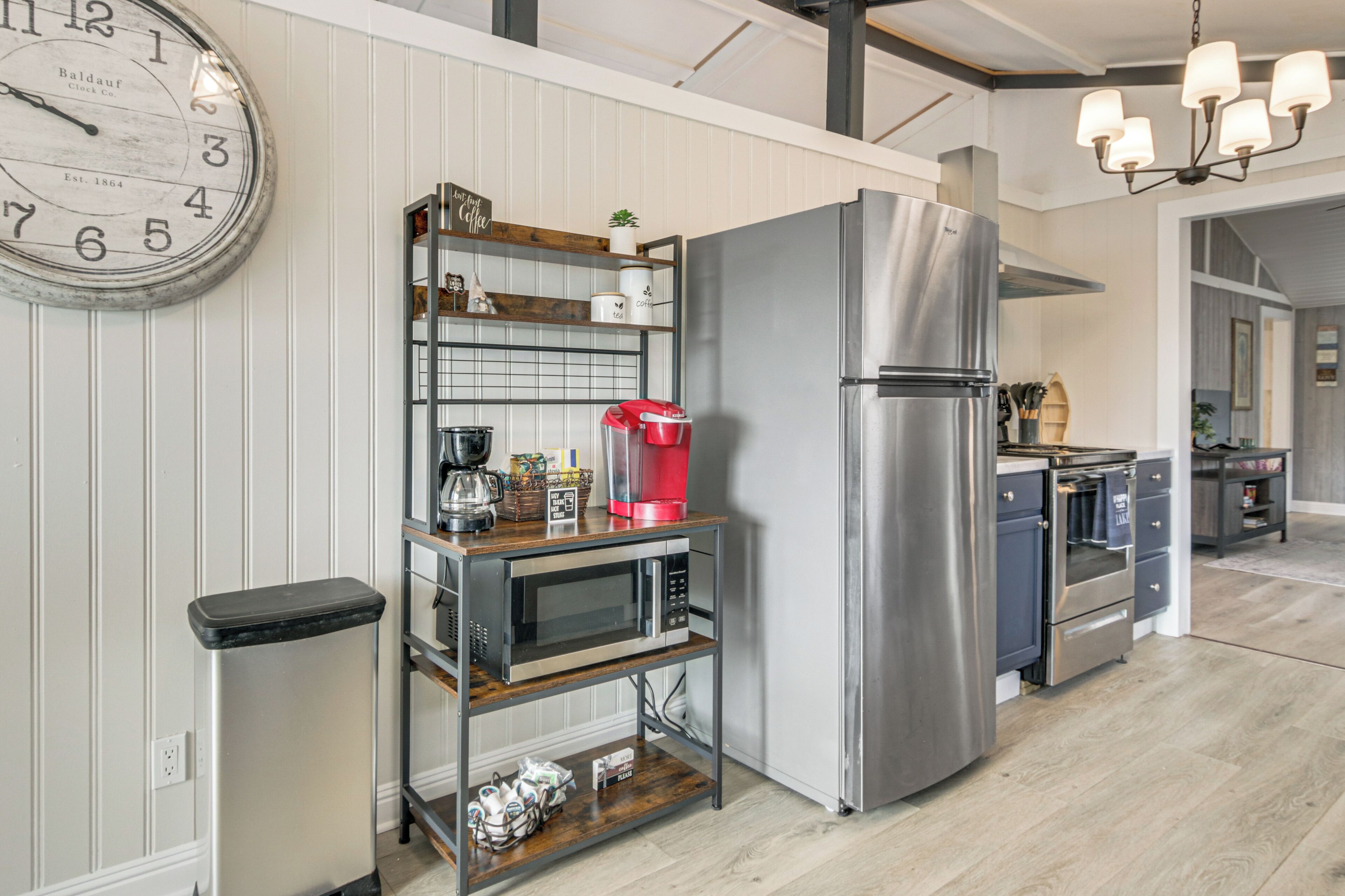 Een keuken met een roestvrijstalen koelkast, een koffiezetapparaat en een klok aan de muur.