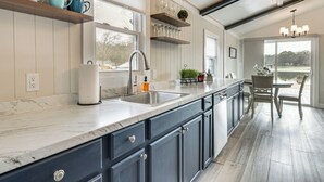Una cocina con armarios azul oscuro, encimera de mármol y un ventanal amplio.