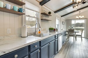 Una cocina con armarios azul oscuro, encimera de mármol y un ventanal amplio.