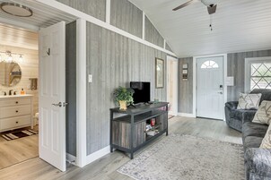 Una sala de estar con un mueble de entretenimiento de madera oscura, un sofá gris y una alfombra estampada.