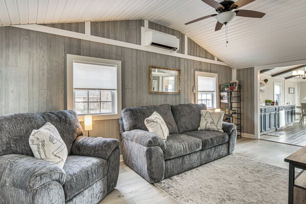 A modern living room with two grey sofas, a wooden ceiling, and a large mirror. - Waterfront Cottage at Cedar Pines Lake (Lancaster)