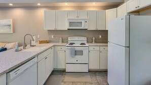 A modern kitchen with white cabinets, a built-in microwave, a stove, and a refrigerator. - < 1 Mi to St Johns River: Serene Family Home! (St. Augustine)
