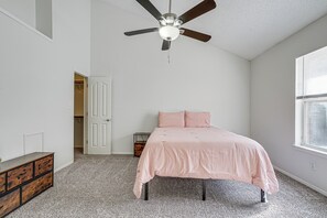 Quarto com cama, ventoinha no teto, cômoda e janela.