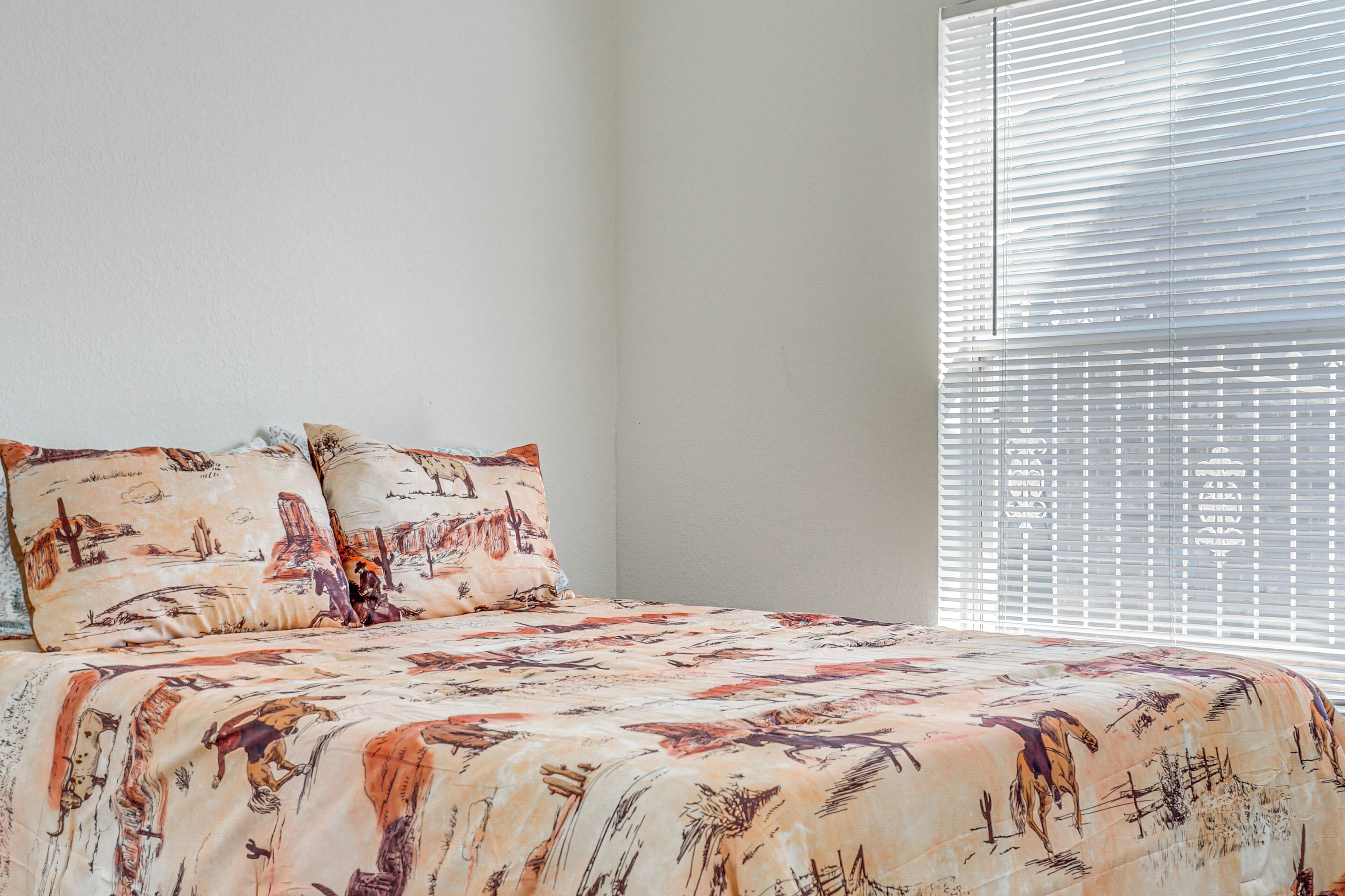 Un dormitorio con una cama, dos almohadas y una ventana con persianas.