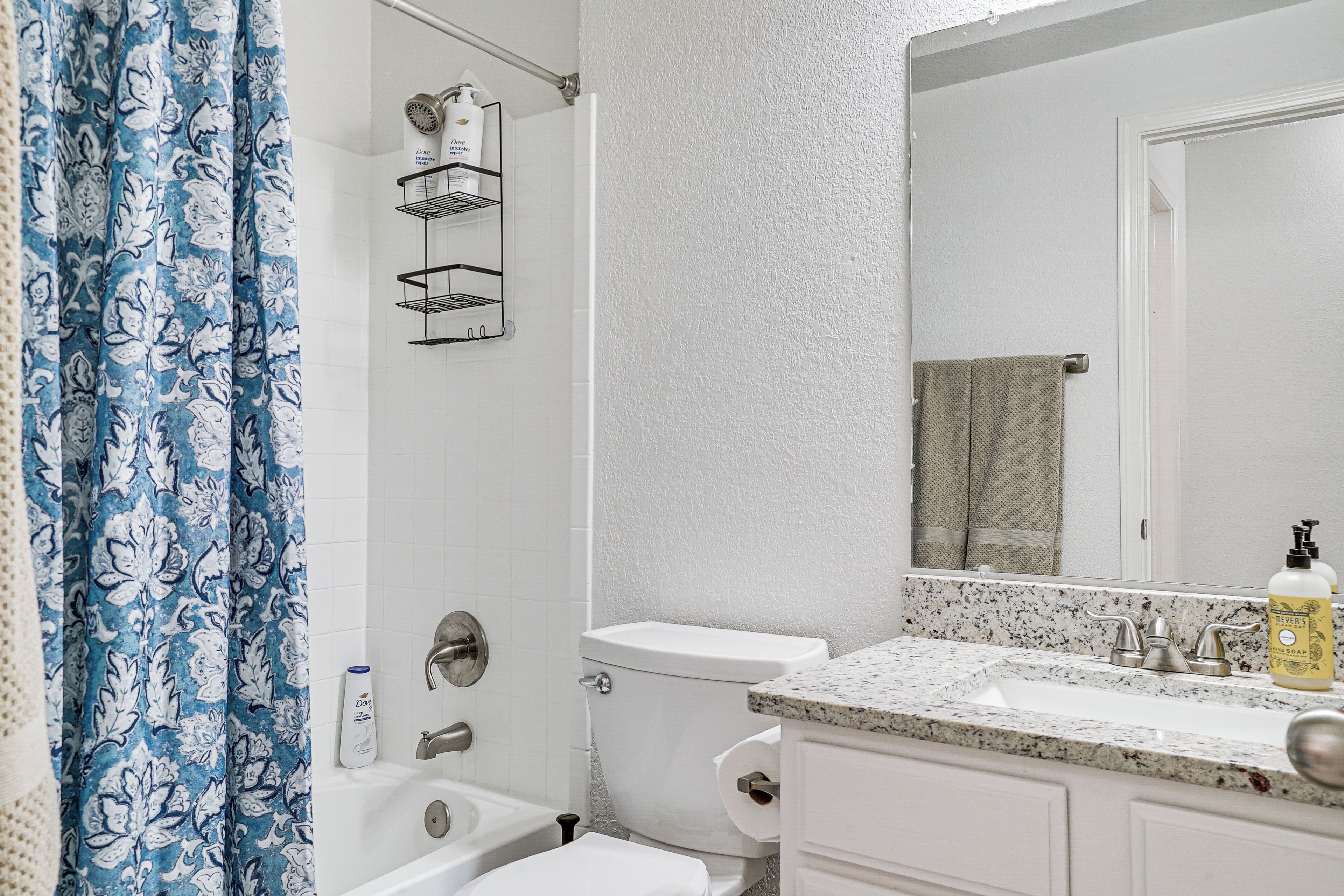 Un baño con ducha, inodoro, lavabo y espejo.