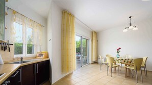 Eine moderne Küche mit Essbereich, ausgestattet mit einem großen Fenster, einer Schiebeglastür und einem Kronleuchter.