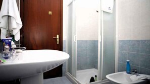 Une salle de bain avec un lavabo blanc, un miroir et un espace douche.