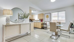 A modern kitchen with a dining area, featuring a central island, a dining table with chairs, and a large window with blinds. - Apt Near Mall, The Big Easy Casino & Beaches! (Hallandale Beach)