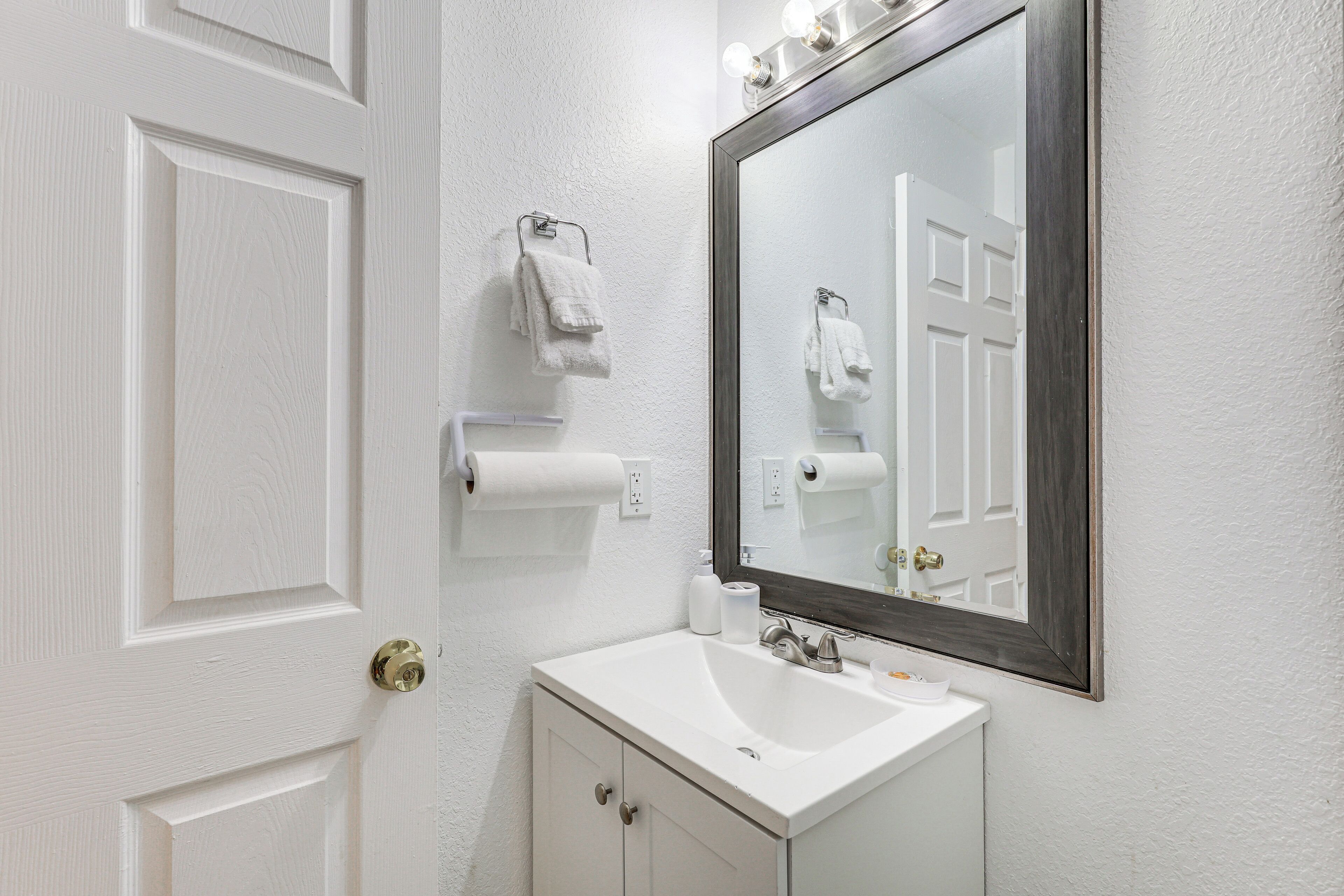 A bathroom with a white sink, a mirror, and a door.