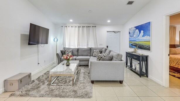 A modern living room with a grey sofa, a coffee table, and a painting on the wall. - Apt Near Mall, The Big Easy Casino & Beaches! (Hallandale Beach)