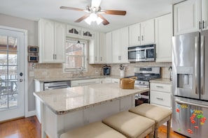 A kitchen with white cabinets, a granite countertop, a stainless steel refrigerator, and a ceiling fan. - Shop, Dine & Explore: 'cozy Cottage' in Louisville (Louisville)