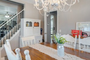 A dining area with a wooden table, white chairs, a chandelier, and a white cabinet with glass doors. - Shop, Dine & Explore: 'cozy Cottage' in Louisville (Louisville)