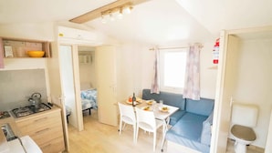 A compact living space with a kitchenette, a dining area, and a seating area. - Mobile home with air conditioning, terrace and pool (Calella de la Costa)