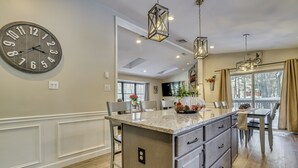 A modern kitchen with a large island, pendant lighting, and a clock on the wall. - Newly Renovated! Peaceful Saylorsburg Home (Saylorsburg)