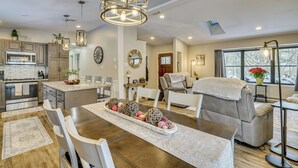 A modern kitchen with a central island, dining area with a wooden table, and a seating area with a sofa and chairs. - Newly Renovated! Peaceful Saylorsburg Home (Saylorsburg)