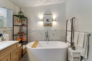 A modern bathroom with a freestanding bathtub, a vanity with a mirror, and a shelf with decorative items. - Dog-friendly Home 6 Mi to Big Boulder Mtn! (Albrightsville)