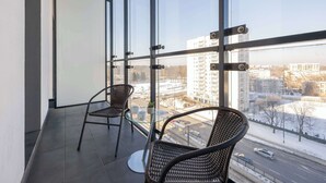Ein Balkon mit zwei Korbstühlen, einem Glastisch und einem Blumentopf.