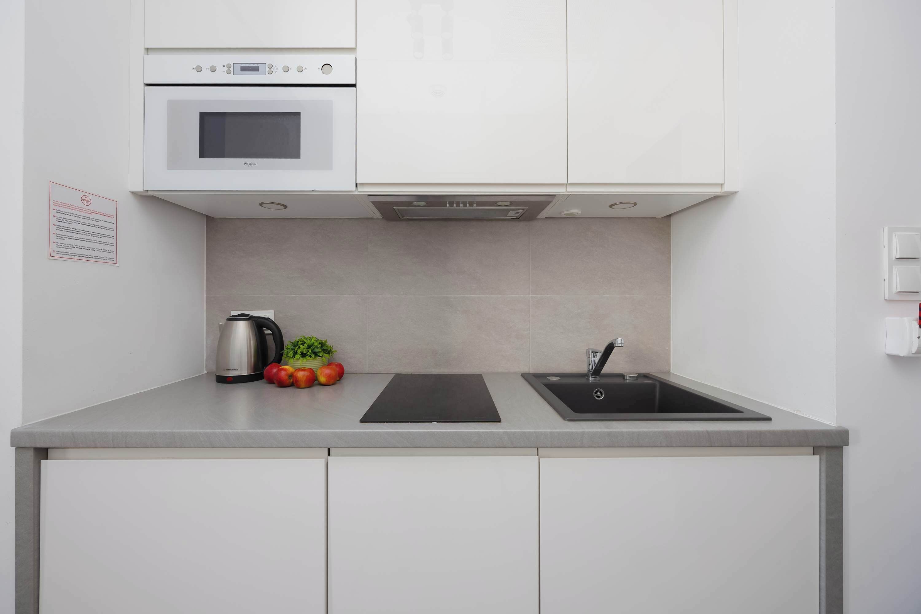 A modern kitchen with a built-in oven, a sink, and a kettle.