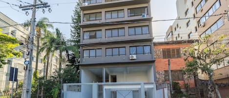 Un immeuble résidentiel à plusieurs étages, doté de balcons, d’une entrée sécurisée et d’un poteau électrique bien visible.