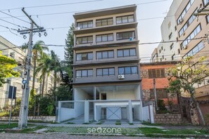 Un immeuble résidentiel à plusieurs étages, doté de balcons, d’une entrée sécurisée et d’un poteau électrique bien visible.