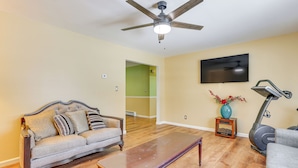 A living room with a sofa, a coffee table, a treadmill, a TV, and a ceiling fan. - Pet Friendly & WFH Ready! Quiet Hudson Valley Apt (Newburgh)