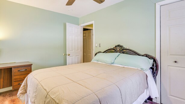 A bedroom with a bed, a wooden nightstand, a ceiling fan, and a door. - Pet Friendly & WFH Ready! Quiet Hudson Valley Apt (Newburgh)