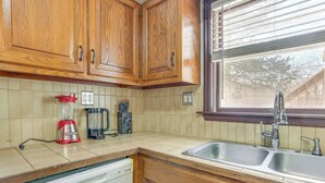 A kitchen with wooden cabinets, a dishwasher, a coffee maker, and a window with blinds. - Pet Friendly & WFH Ready! Quiet Hudson Valley Apt (Newburgh)
