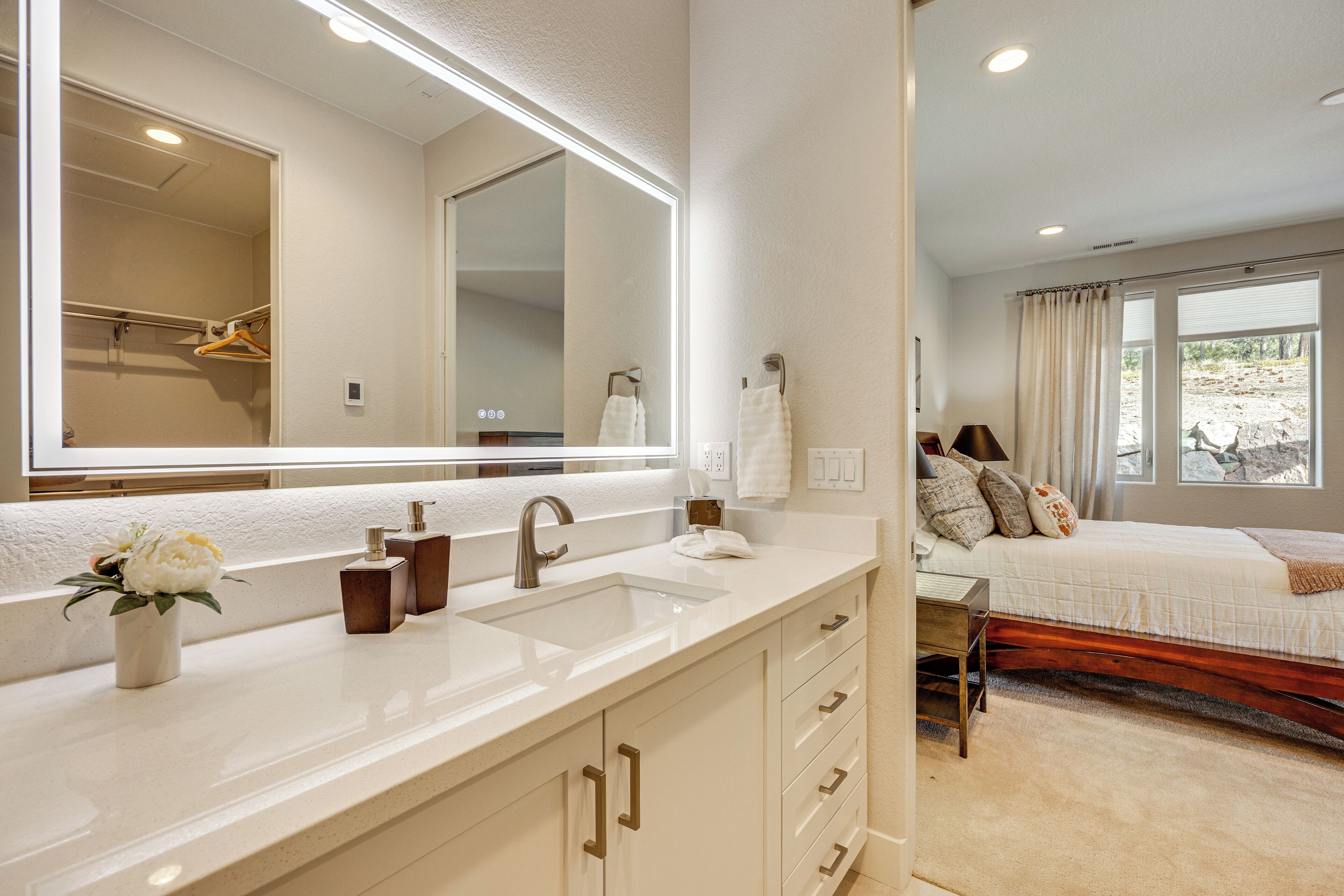 A modern bathroom with a large mirror, dual sinks, and a vanity with storage drawers.