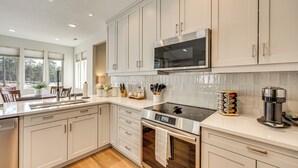 A modern kitchen with white cabinetry, stainless steel appliances, and a large window providing natural light. - Trail Access On-site! Wooded Colorado Springs Gem (Colorado Springs)