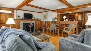 Una sala de estar acogedora con chimenea, muebles de madera y televisor.