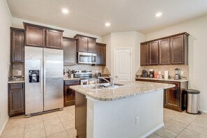 A modern kitchen with dark wooden cabinets, stainless steel appliances, and a granite countertop island. - Cozy & Family-friendly 2-story Home (Jarrell)