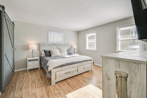 Une chambre à coucher avec un lit, des tables de chevet, une commode et une fenêtre.