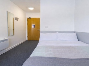 A hotel room with a large bed, a wooden door, and a white wall. - Cathedral Road by UTDM (Derby)