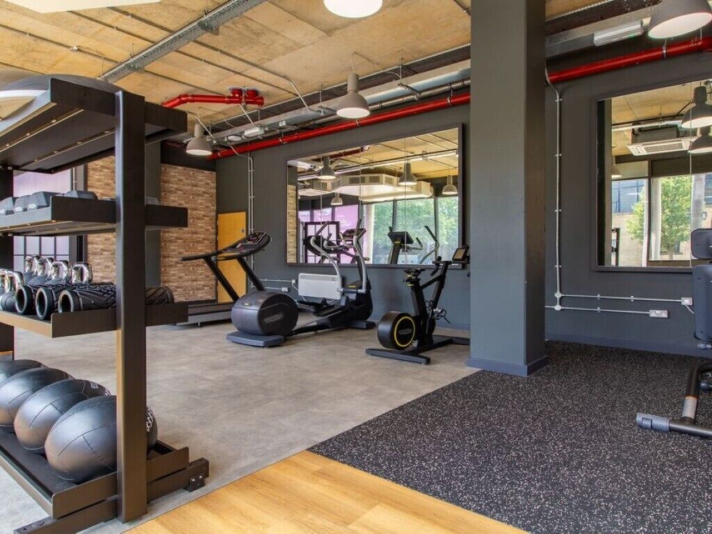 Une salle de sport équipée de matériel d’exercice, d’un miroir et d’une fenêtre.