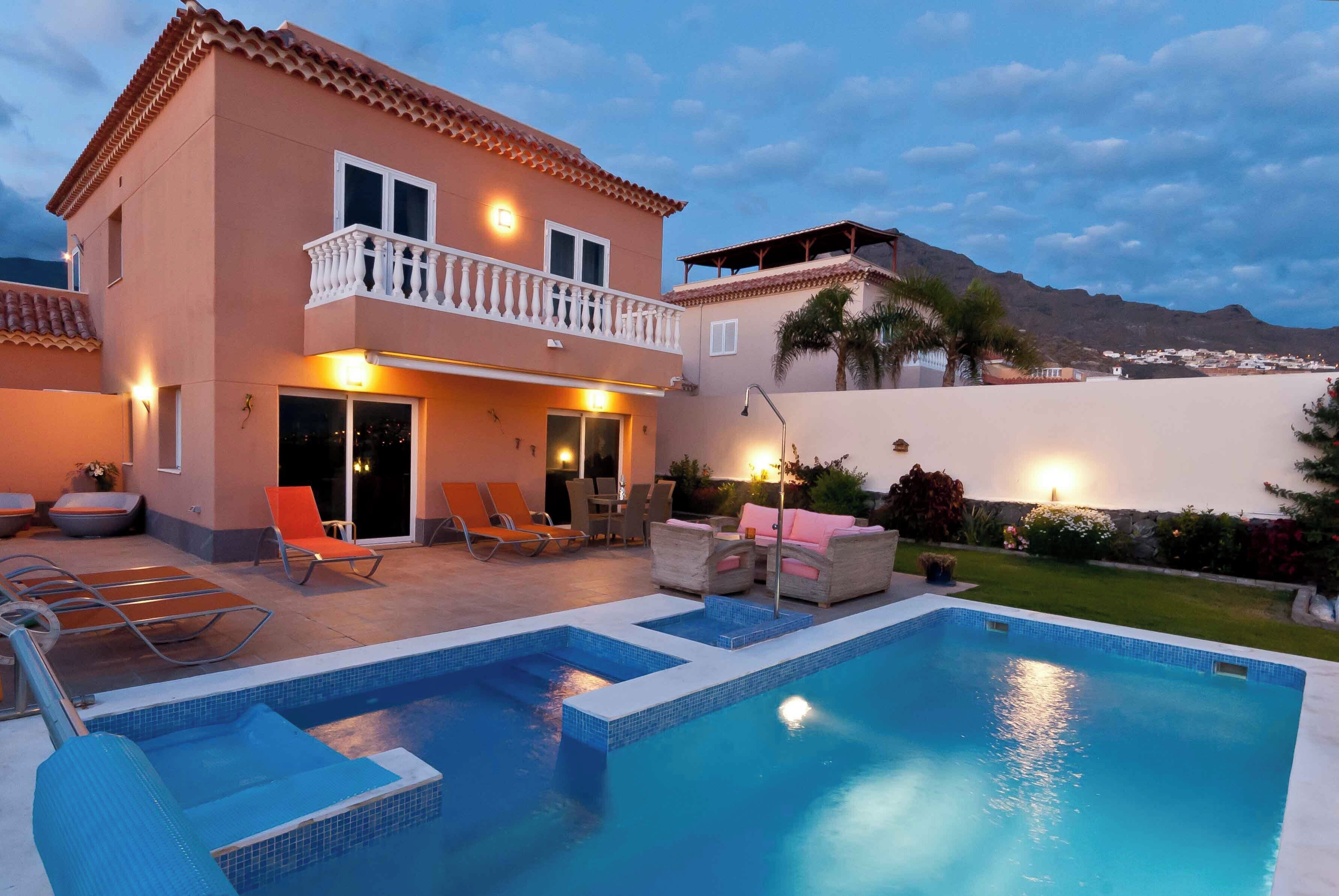 A two-story house with a swimming pool, outdoor furniture, and a balcony.