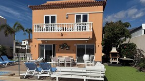 Un bâtiment à deux étages doté d’un balcon, d’un espace extérieur aménagé pour s’asseoir, d’une piscine et d’une pelouse bien entretenue.