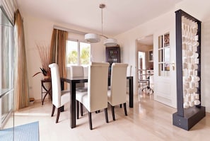 A modern dining area with a table and chairs, a chandelier, and a view of the outdoors.
